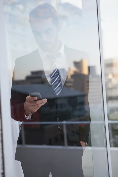 Businessman sending a text seen through window — Stock Photo, Image