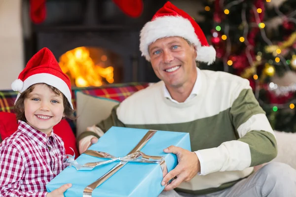 Syn dává otec vánoční dárek na gauči — Stock fotografie
