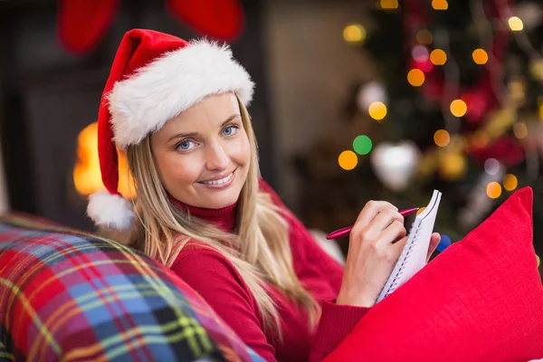 Blonde assise sur le canapé écrivant sa liste de Noël — Photo