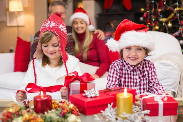 Festlig liten syskon öppna en gåva framför sina föräldrar — Stockfoto