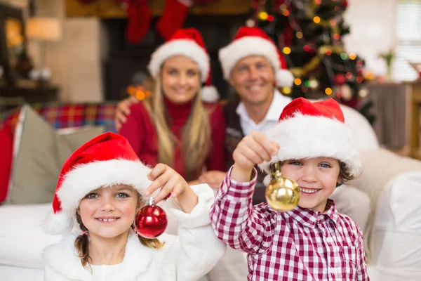 Bonitos irmãozinhos usando chapéu de Papai Noel segurando bugigangas — Fotografia de Stock