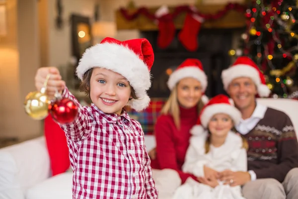 Syn sobie santa hat gospodarstwa bombki przed rodziną — Zdjęcie stockowe