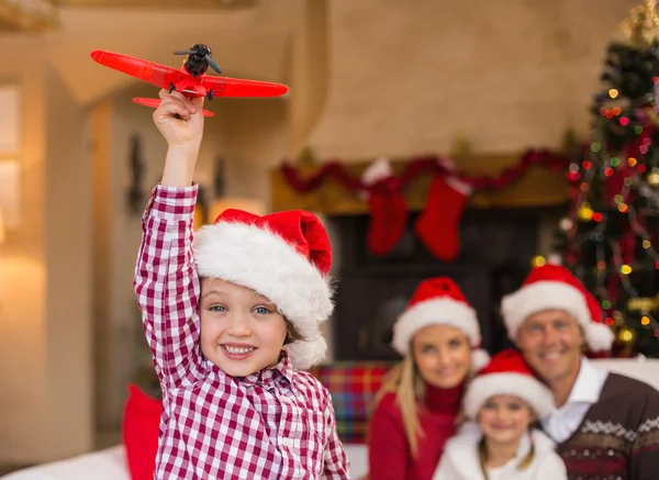 Boy playing with toy airplane in front of his family on couch — Stock Photo, Image