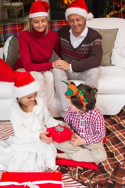 Les parents assis sur le canapé regardant les enfants ouvrir leurs cadeaux — Photo