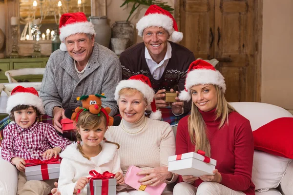 Portrét šťastné rozšířené rodiny v santa hat drží dary — Stock fotografie