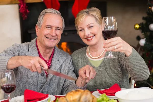 Hombre tallando pollo mientras su esposa bebe vino tinto — Foto de Stock