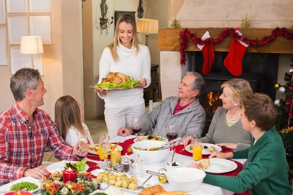 Mujer sosteniendo pavo asado con la familia en la mesa de comedor —  Fotos de Stock