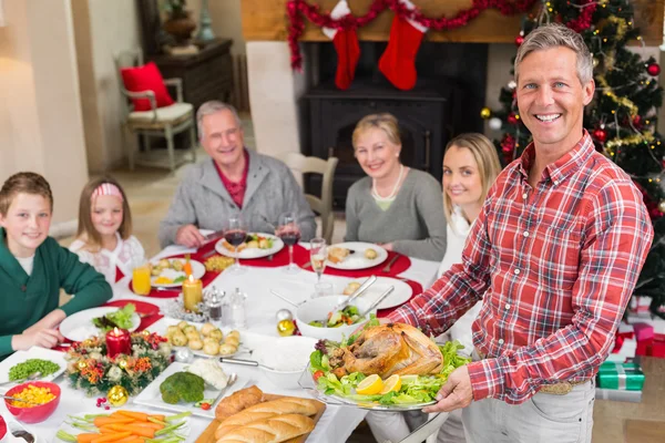 Homem segurando peru assado com a família na mesa de jantar — Fotografia de Stock