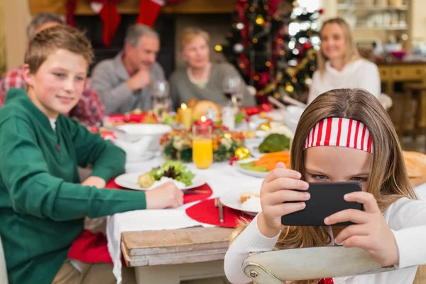 Niña sosteniendo teléfono inteligente durante la cena de Navidad — Foto de Stock