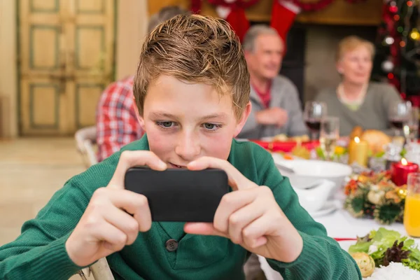 Jonge jongen smartphone houden tijdens kerstdiner — Stockfoto