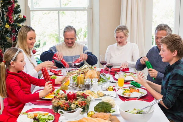 Famiglia tirando cracker di Natale a tavola — Foto Stock