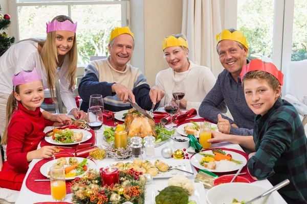 Grootvader in feest hoed snijwerk kip tijdens het diner — Stockfoto