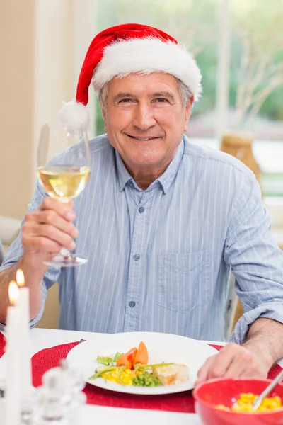 Χαμογελώντας ώριμος άνδρας σε santa καπέλο φρυγανίσματος με λευκό κρασί — Φωτογραφία Αρχείου