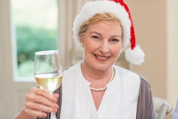 Uśmiechnięta dojrzała kobieta w santa kapeluszu toasting z białym winem — Zdjęcie stockowe