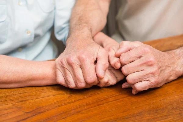 Senior couple holding hands on table — Stock Photo, Image