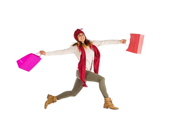 Smiling brunette jumping with gifts bags — Stock Photo, Image