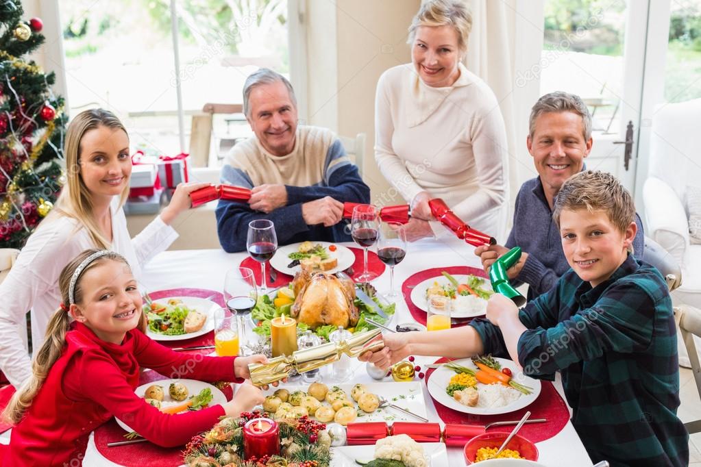Family pulling christmas crackers at the dinner table — Stock Photo © Wavebreakmedia #60838487