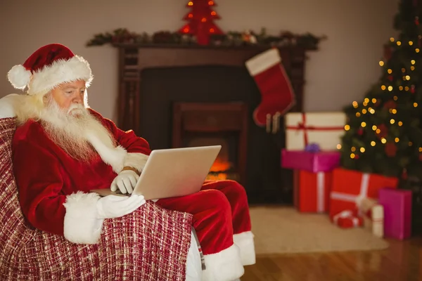 Santa usando el ordenador portátil en el sofá en Navidad — Foto de Stock