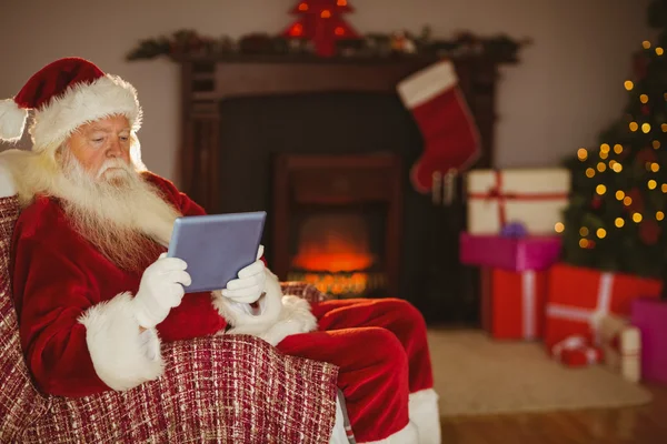 Santa med tablett på soffan vid jul — Stockfoto
