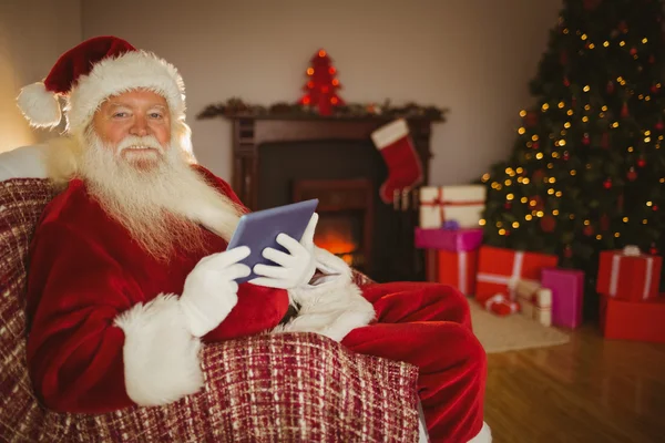 Vrolijke santa met behulp van Tablet PC op de Bank — Stockfoto