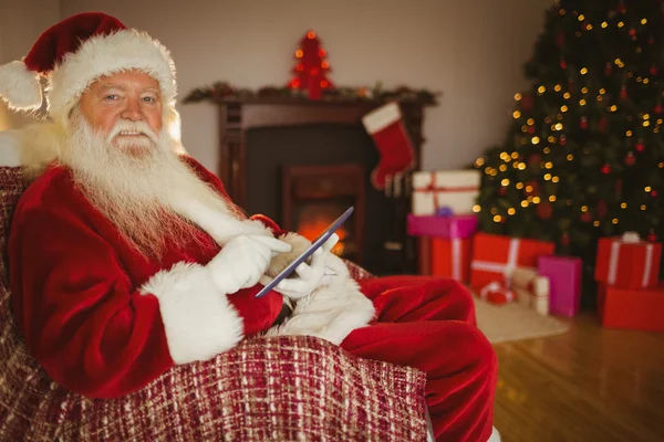 Happy santa dotýkal tabletu na gauči — Stock fotografie