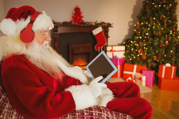 Santa, poslech hudby a dotýkal tabletu — Stock fotografie