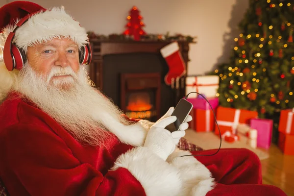 Glimlachend santa luisteren muziek met zijn smartphone — Stockfoto