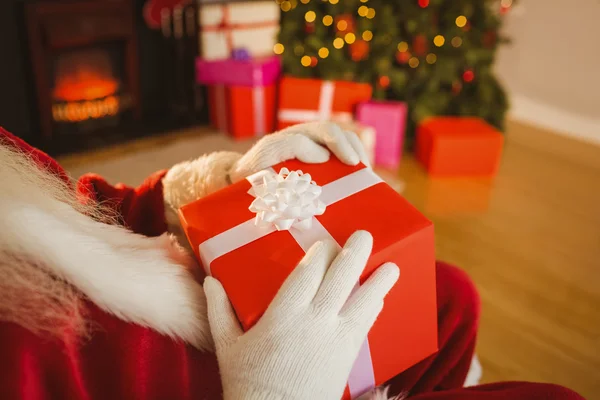 Julenissen holder en rød gave. – stockfoto
