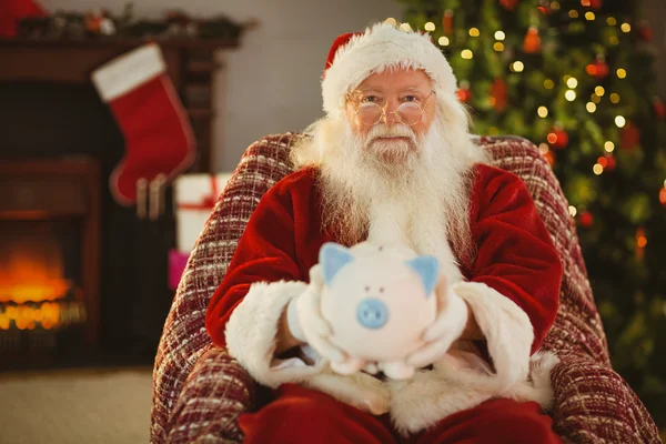 Lächelnder Weihnachtsmann bietet Sparschwein an — Stockfoto