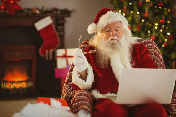 圣诞老人在扶手椅上使用笔记本电脑 — 图库照片