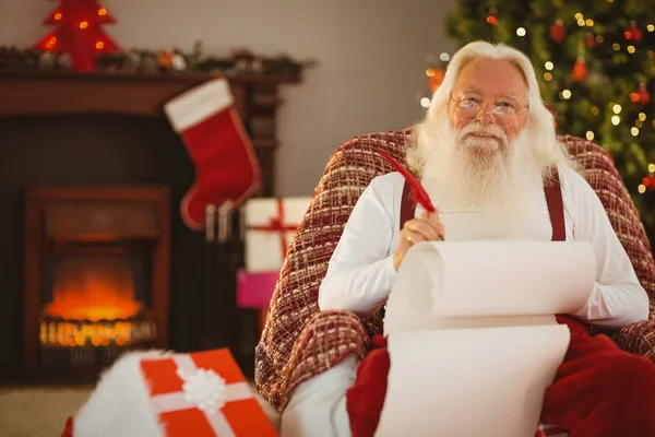 微笑在扶手椅上写清单的圣诞老人 — 图库照片