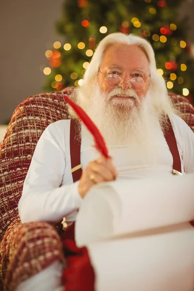 Happy santa writing list on the armchair — Stock Photo, Image