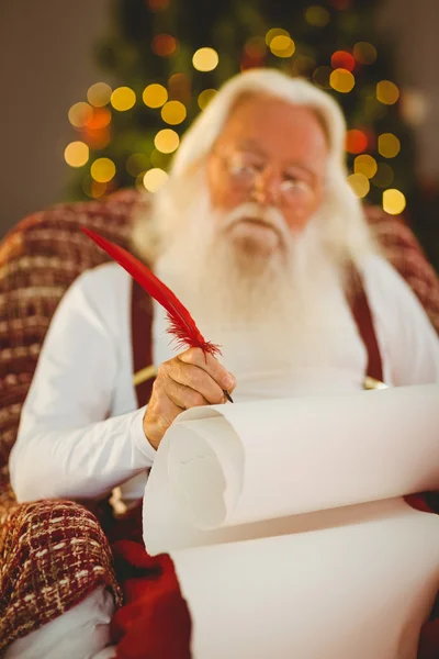 Konzentrierte Weihnachtsmann-Schreibliste auf dem Sessel — Stockfoto