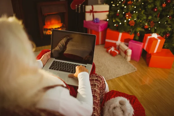 Koltukta oturan ve dizüstü bilgisayarda yazarak Santa — Stok fotoğraf