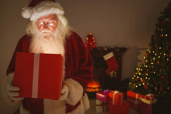 Santa claus přináší dárek svítící — Stock fotografie