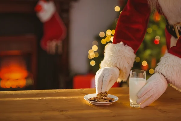 Santa claus plukken cookie en een glas melk — Stockfoto