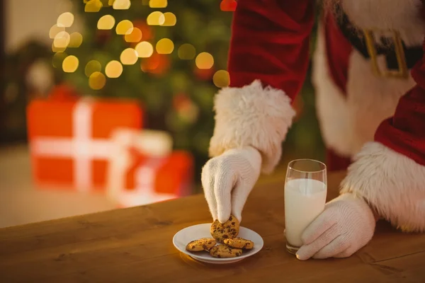 Weihnachtsmann pflückt Plätzchen und Glas Milch — Stockfoto