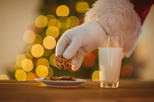 Hand van santa claus plukken cookie — Stockfoto