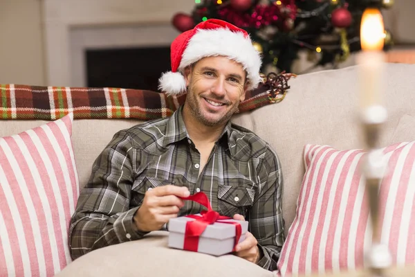 Gelukkig man in Kerstman hoed openen een geschenk — Stockfoto