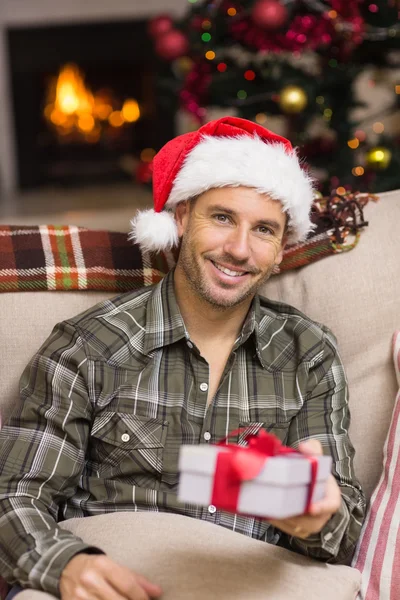 Glimlachende man in Kerstman hoed tonen een geschenk — Stockfoto