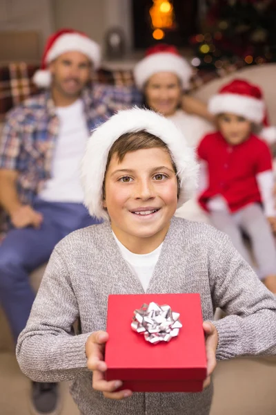 Filho festivo segurando presente na frente de sua família — Fotografia de Stock