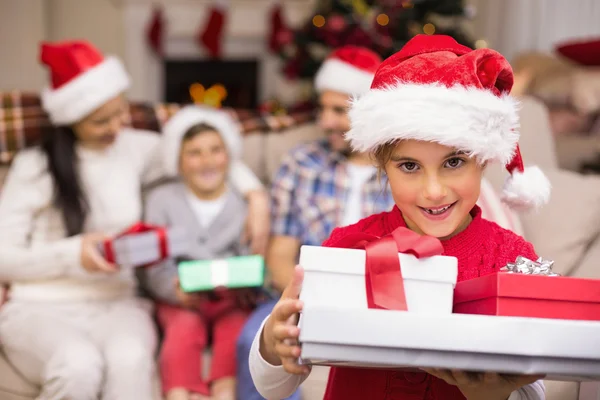 Figlia festiva che tiene mucchio di regali con la sua famiglia dietro — Foto Stock
