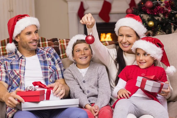 Família festiva vestindo chapéu de Papai Noel no sofá — Fotografia de Stock