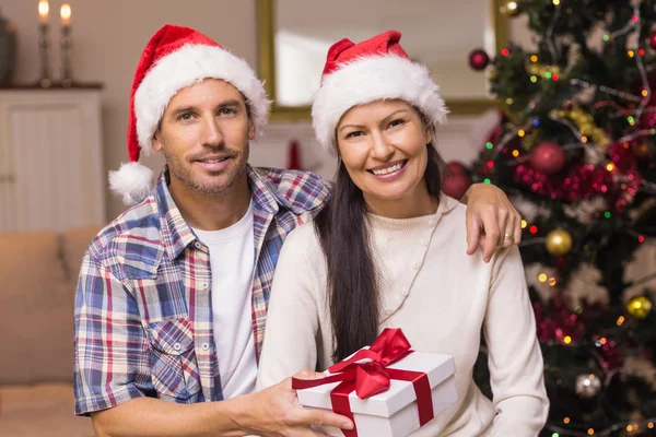 Sonriente pareja en santa hat holding presente —  Fotos de Stock