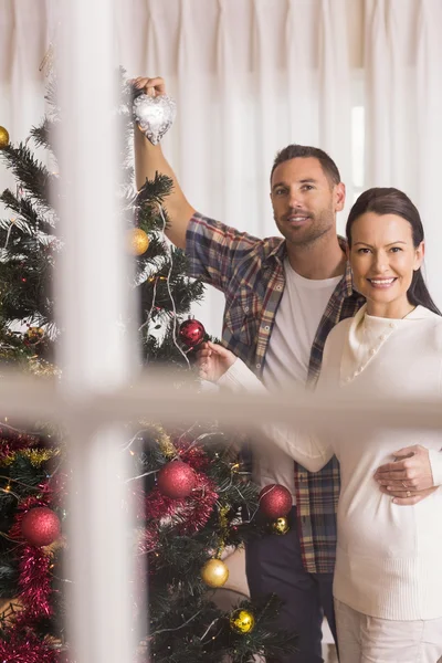 Couple souriant décorer l'arbre de Noël ensemble — Photo