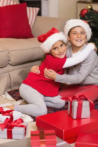 Брат и сестра обнимаются возле подарков — стоковое фото