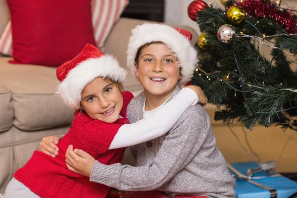 Hermano sonriente y hermana abrazándose cerca del árbol de Navidad —  Fotos de Stock