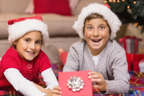 Zaskoczony bracie i w santa hat siostra otwierając prezent — Zdjęcie stockowe