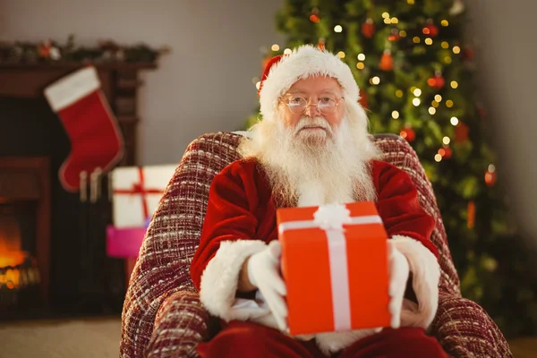 Santa claus offering a red gift Royalty Free Stock Images