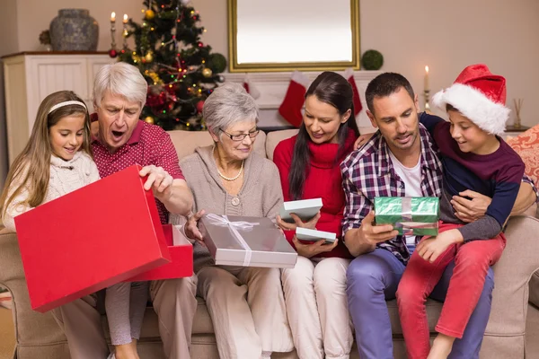 Multi pokolenie rodziny otwieranie prezentów na kanapie — Zdjęcie stockowe